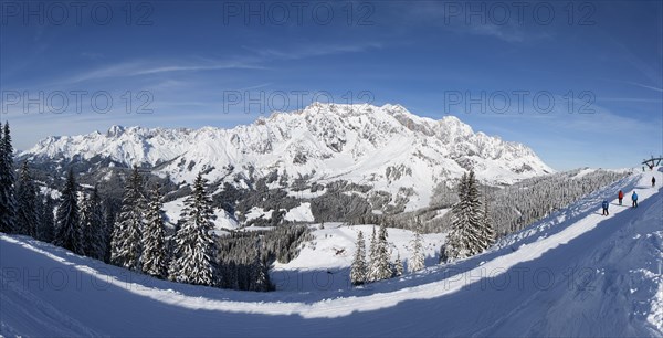 Skiers on ski slope in front of mountain scenery