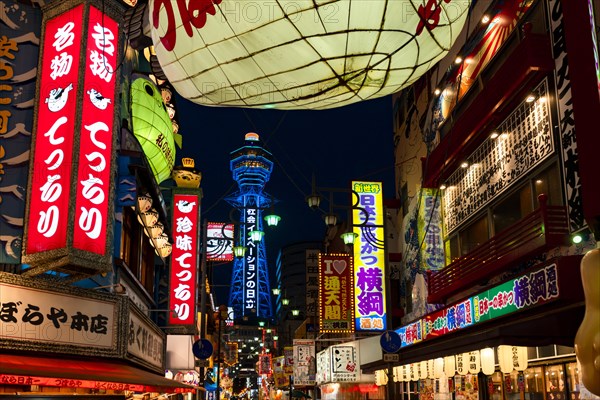 Many colorful neon signs in a pedestrian zone with shops and restaurants