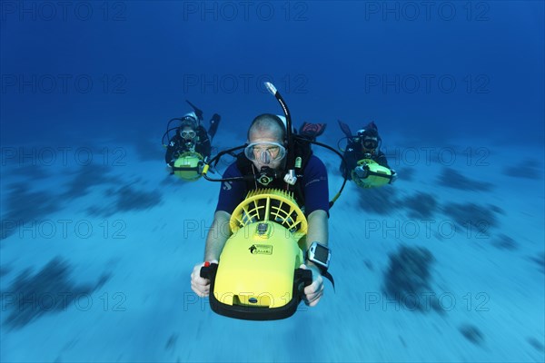 Divers with diver propulsion vehicles exploring a coral reef