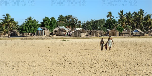 Malagasy woman and her two children walking on the beach