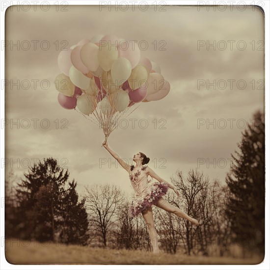 Young woman holding lots of balloons