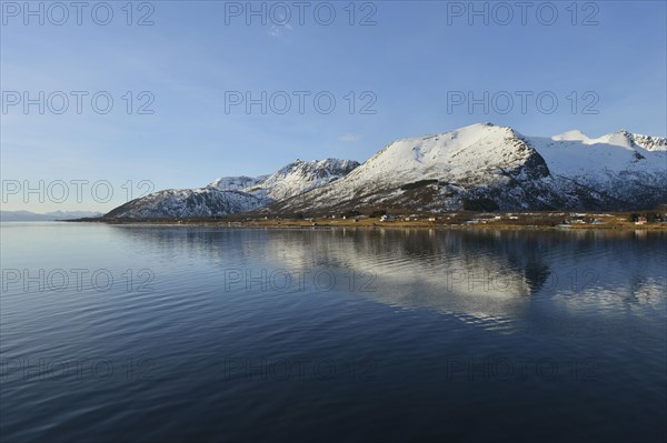 Snow-capped mountains of the southern island of Andoya reflected in Risoysund