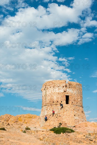Three people walking down from a Genoese tower
