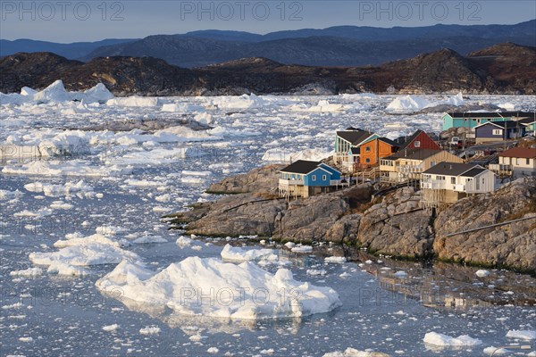 Colourful timber houses by the sea with iceberg fragments