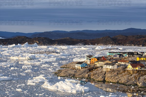 Colourful timber houses by the sea with iceberg fragments