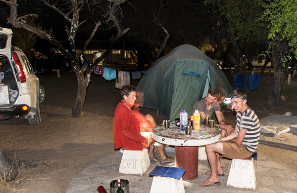 Mother with two teenagers on a campsite in front of a tent