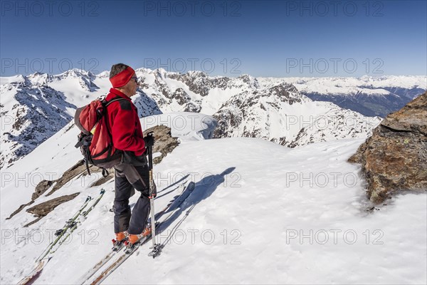 Ski tourer on the summit ridge with overhanging snow