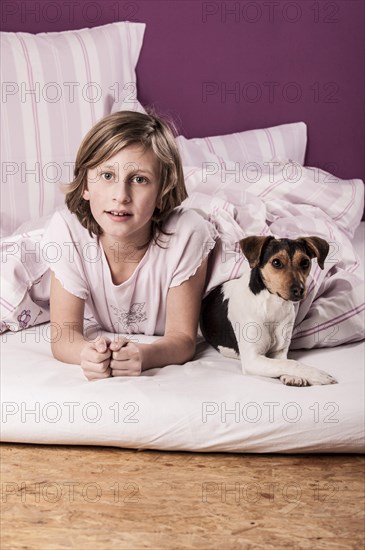 Girl lying in bed with a Danish Swedish Farmdog