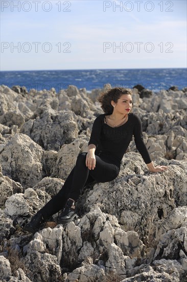 Teenager sitting on rocks by the sea