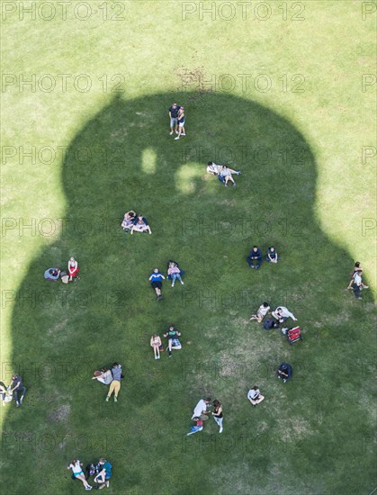 Tourists cooling off in the shade of the Leaning Tower of Pisa