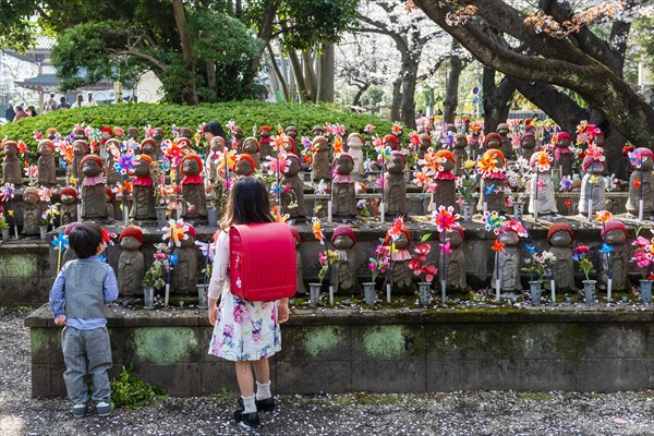 Two schoolchildren in front of Jizo statues with red caps