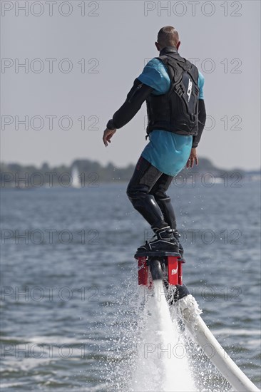 Flyboarder on the water jet of a jet ski