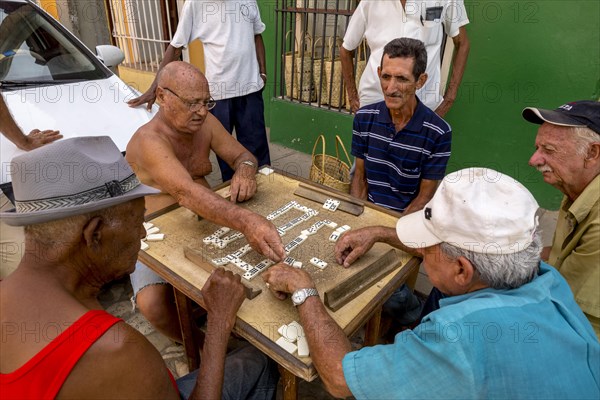 Cuban men playing dominoes at a table outside