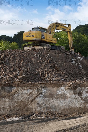Excavator standing on a large rubble heap