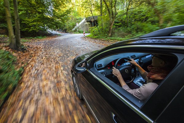 Car driving on a street covered with leaves