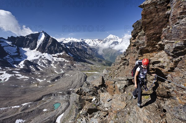 Hiker climbing the Croda di Cengles mountain on the fixed rope route above the Duesseldorfhuette mountain hut in Sulden