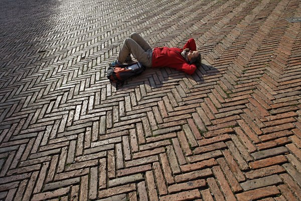 Tourist lying in the Piazza del Campo square