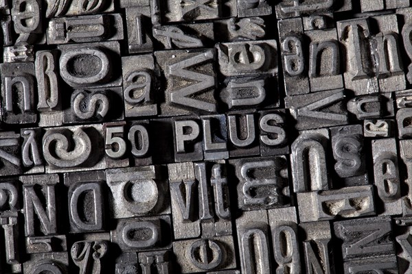 Old lead letters forming the term '50 PLUS'