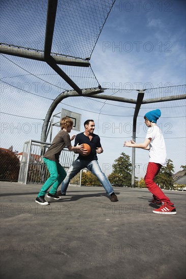 Two cool boys playing basketball with their father