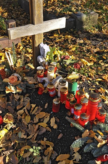 Grave with votive candles and autumn leaves on the Ostfriedhof or East Cemetery