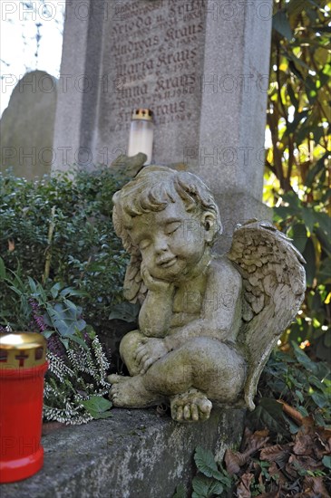 Putto and votive candle with autumn leaves on the Ostfriedhof or East Cemetery