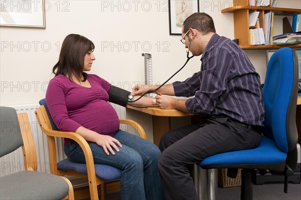 GP doctor checking a pregnant woman's blood pressure