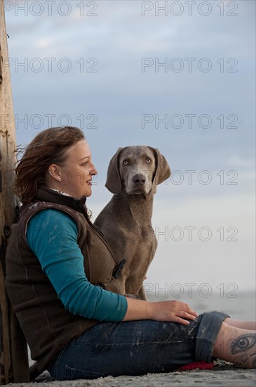 Woman with a Weimaraner on the beach