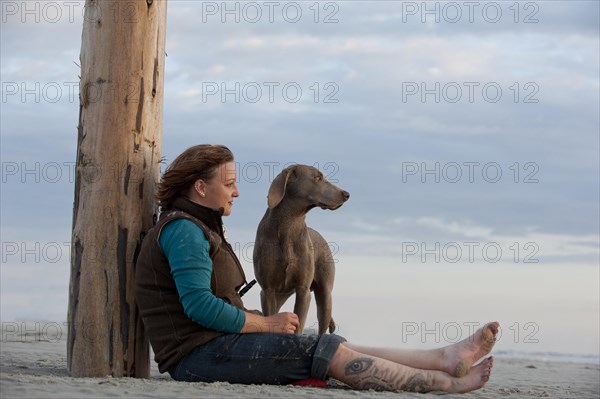 Woman with a Weimaraner on the beach