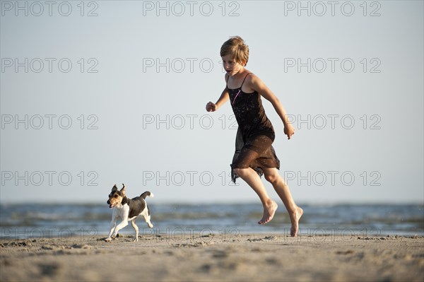 Girl running with a Dansk-Svensk Gardshund or Danish-Swedish Farmdog on the beach