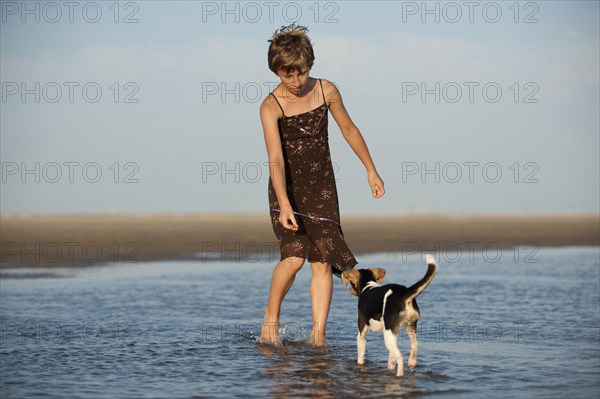 Girl playing with a Dansk-Svensk Gardshund or Danish-Swedish Farmdog on the beach