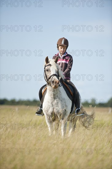 Girl riding a pony in dunes