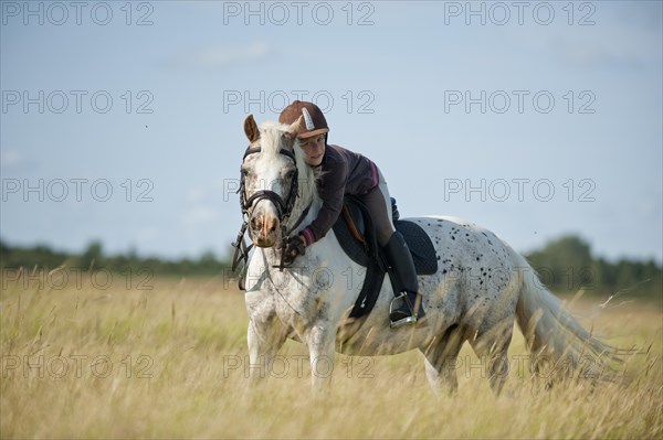 Girl riding a pony in dunes