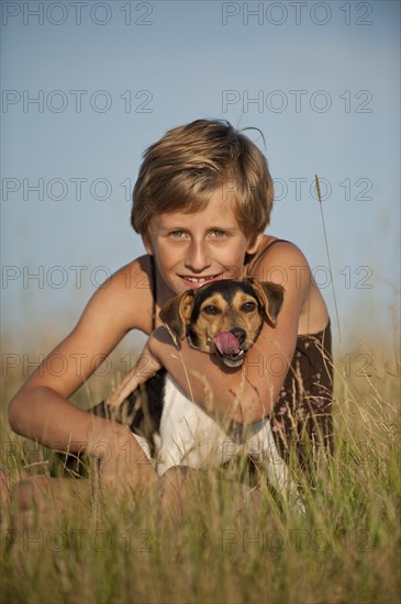 Girl sitting with a Dansk-Svensk Gardshund or Danish Swedish Farmdog in a meadow