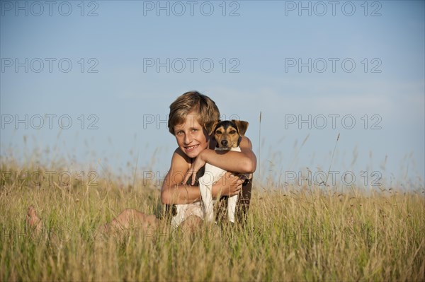 Girl sitting with a Dansk-Svensk Gardshund or Danish Swedish Farmdog in a meadow