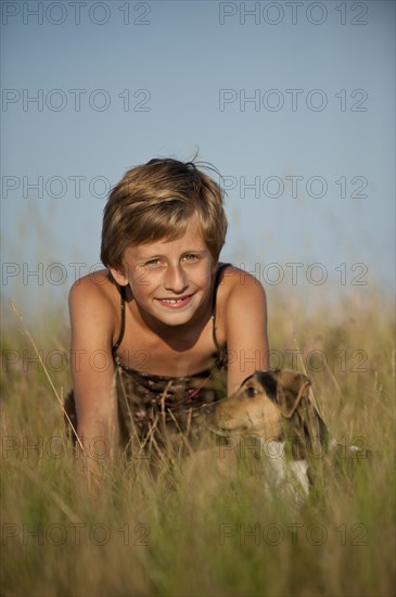 Girl sitting with a Dansk-Svensk Gardshund or Danish Swedish Farmdog in a meadow