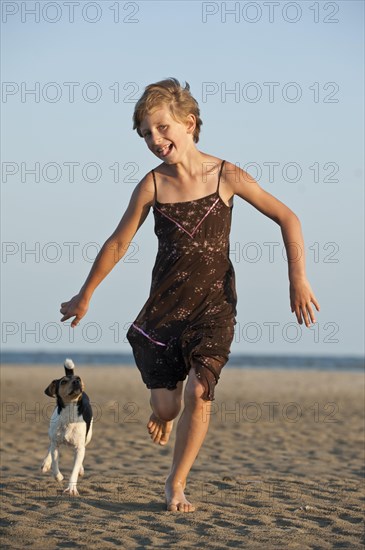 Girl running with a Dansk-Svensk Gardshund or Danish-Swedish Farmdog on the beach