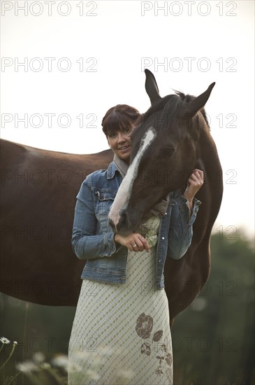 Woman standing beside a Hanoverian horse in a meadow