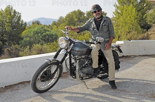 Elderly man sitting on a Triumph Tiger 500cc motorbike