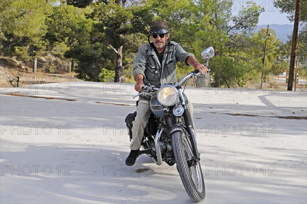 Elderly man riding a Triumph Tiger 500cc motorbike