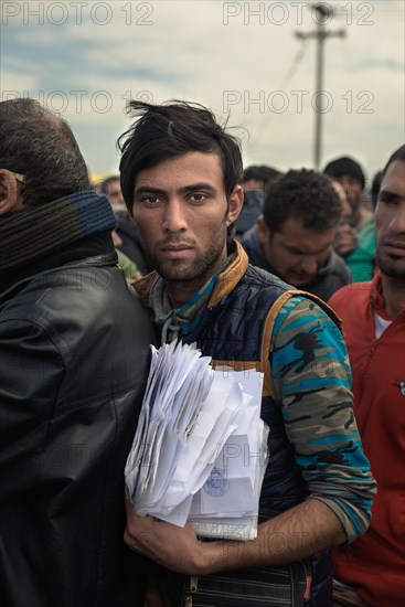 Refugee with a pile of papers in line for a visa