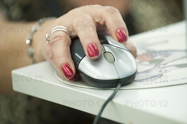 Hand of an elderly woman operating a computer mouse