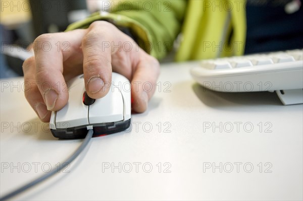 Workers hand on a computer scroll mouse.