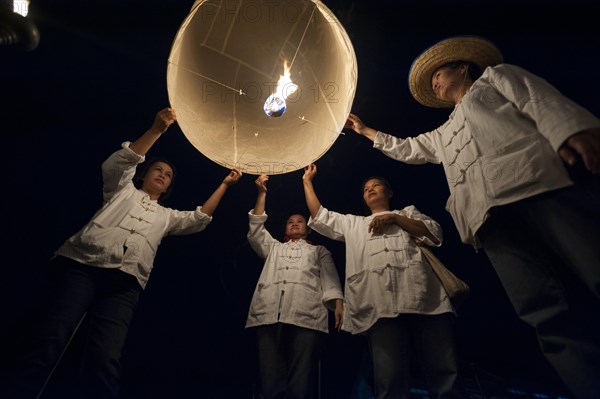 People releasing a Kongming lantern or sky lantern for luck during the Loi Krathong or Loy Gratong Festival