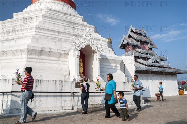 People with offerings walking around a Pagoda or Chedi