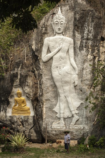 Elderly woman standing in front of Buddha sculptures