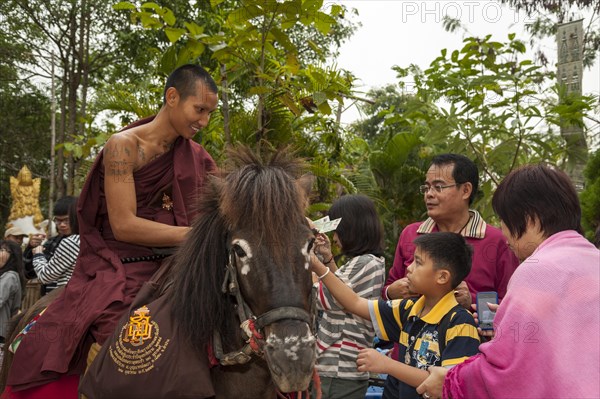 Buddhist monk on horseback collecting alms in the morning