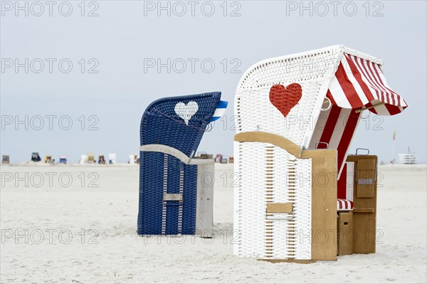 Roofed wicker beach chairs with hearts on the beach at Norddorf