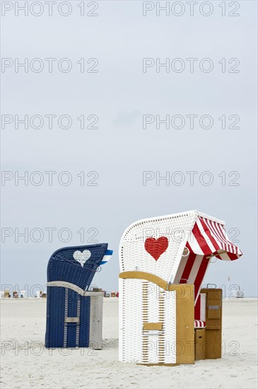 Roofed wicker beach chairs with hearts on the beach at Norddorf