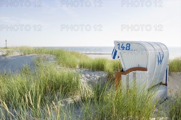 Dunes and white roofed wicker beach chair