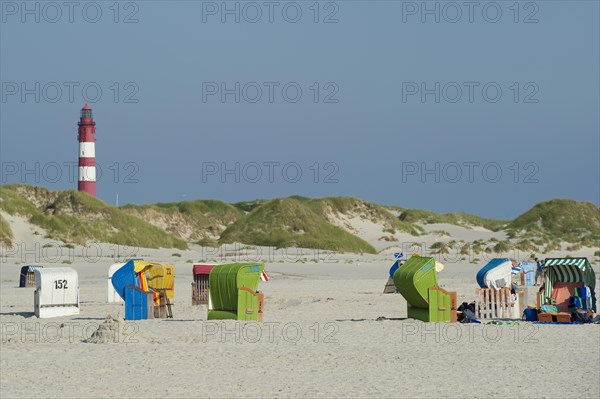 Roofed wicker beach chairs and lighthouse at Nebel